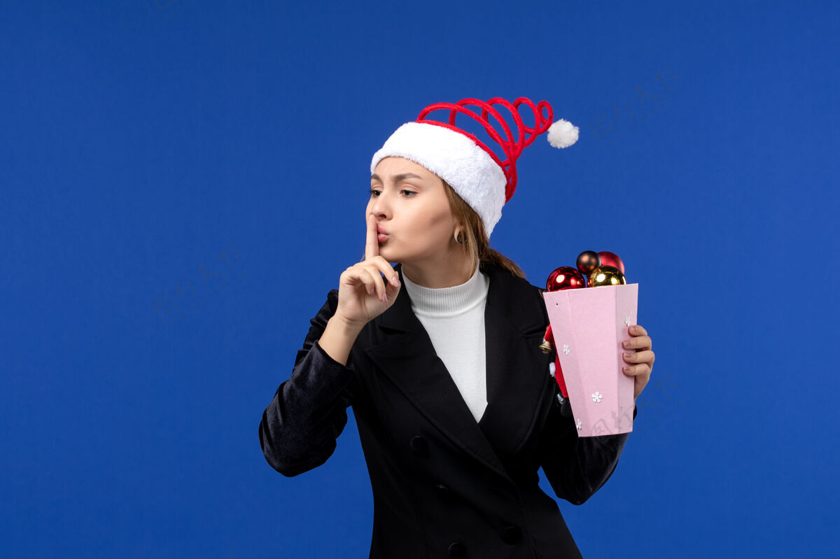 圣诞节前视图年轻女性与树玩具蓝色墙壁新年假期情感色彩人颜色正面