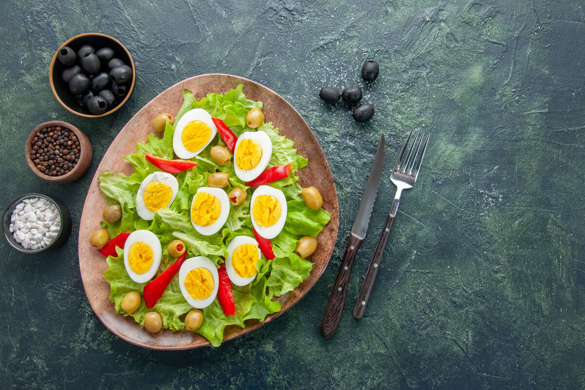晚餐俯视图美味的鸡蛋沙拉与绿色沙拉橄榄和调味品在黑暗的背景煮鸡蛋顶部膳食