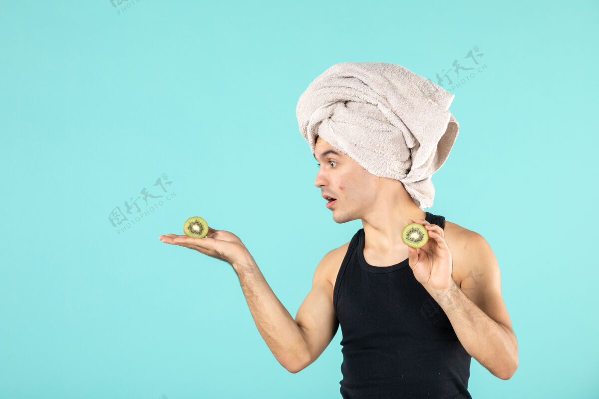 人正面图蓝色背景上的年轻男性 有猕猴桃片和丘疹洗澡正面干净