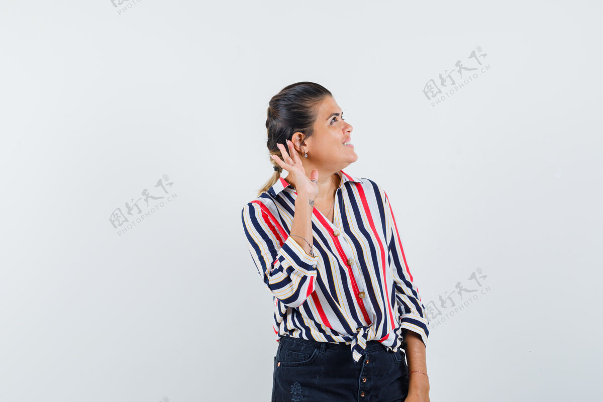 肖像一个穿着衬衫 裙子的女人把手放在耳朵后面 看上去很好奇现代脸时尚