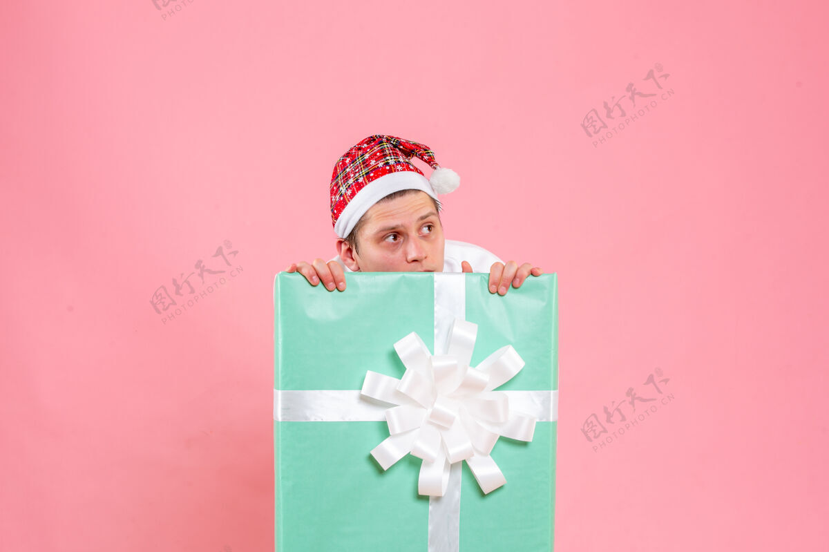 睡衣正面图：穿着白色衬衫的年轻男性 粉色背景上隐藏着礼物正面圣诞节情感