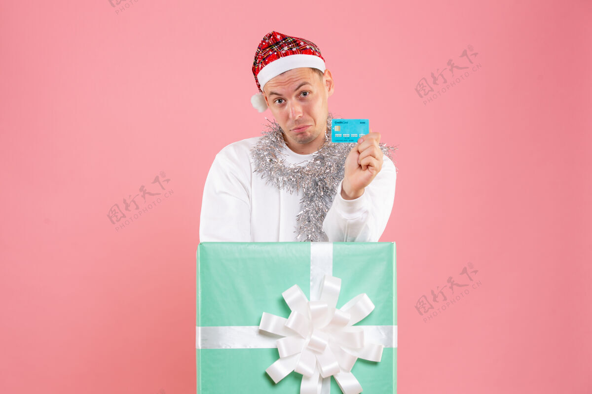 银行正面图里面的年轻男性手持粉色背景的银行卡卡片情感肖像