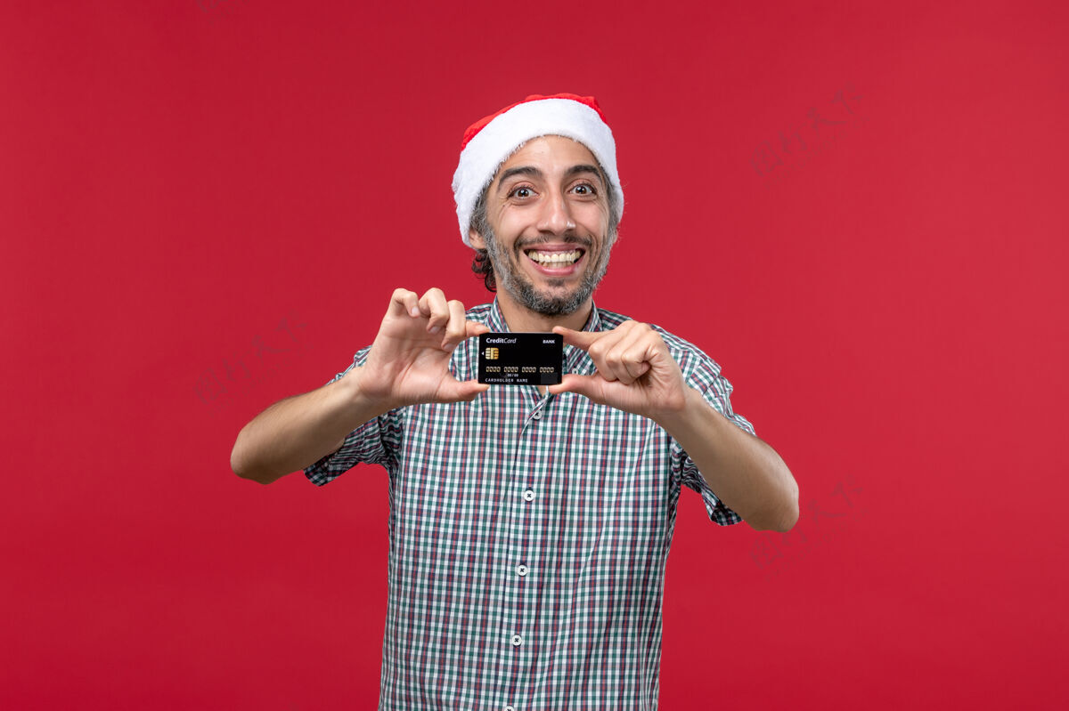 肖像正面图年轻男子手持银行卡 在红色背景上微笑男人年轻男性视图