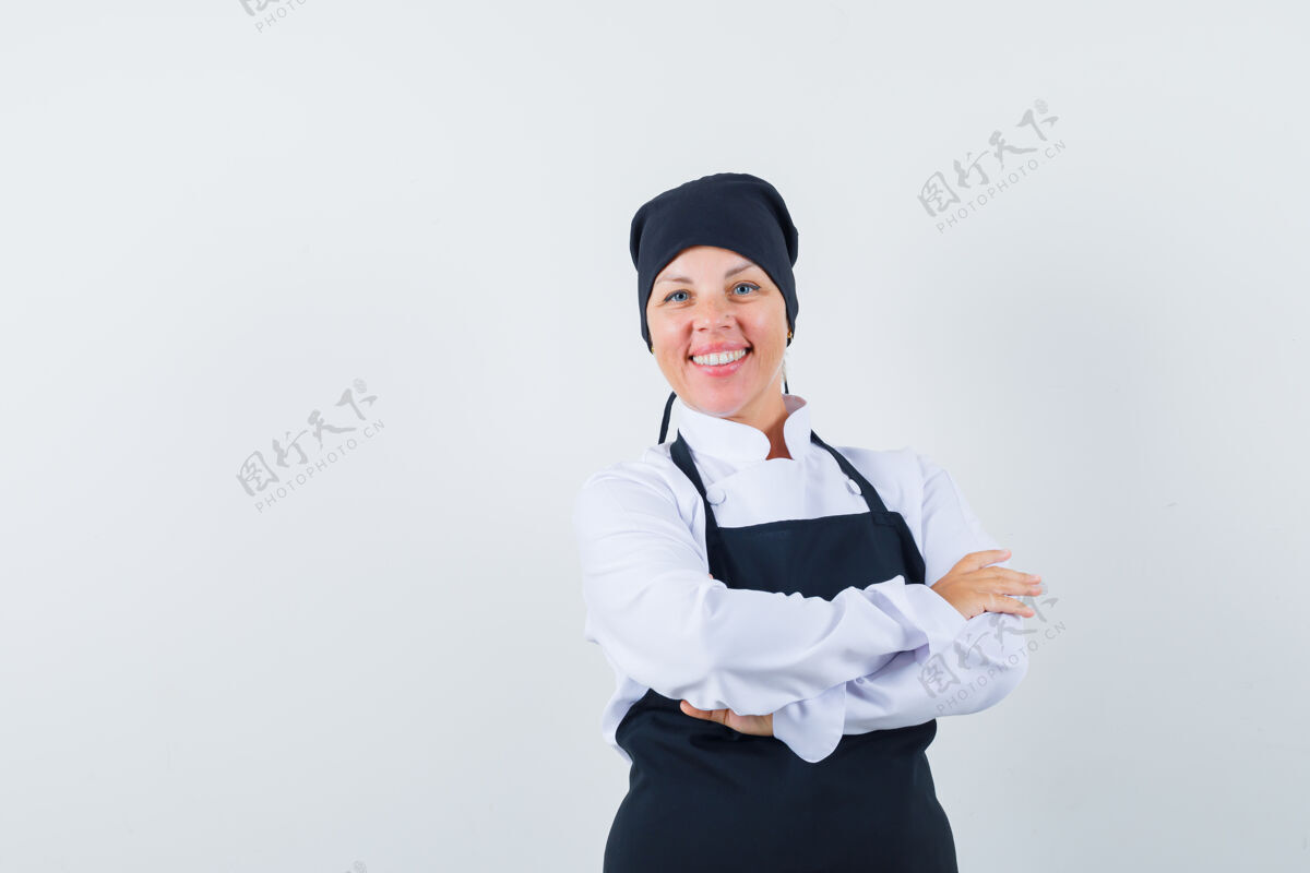 交叉金发女人双臂交叉站着 身着黑色厨师制服 面带微笑 看上去很漂亮头部时尚漂亮