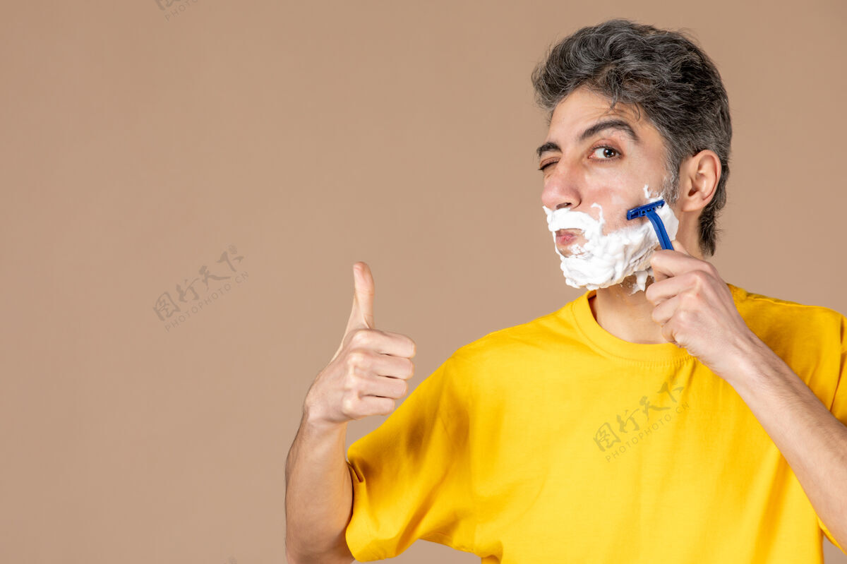 人正面图：年轻男性在粉色背景上剃着泡沫脸牙刷人身体护理