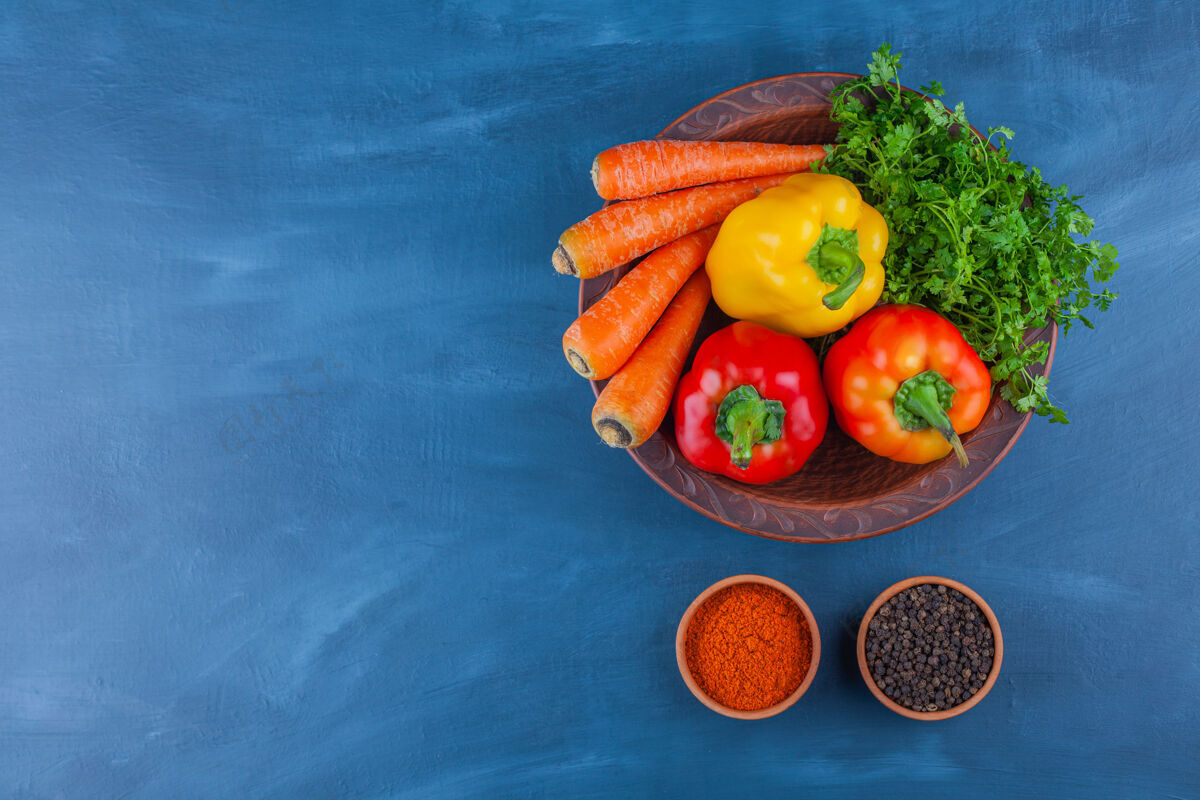 胡椒蓝色桌子上摆着一盘各种新鲜成熟的蔬菜胡萝卜五颜六色食物