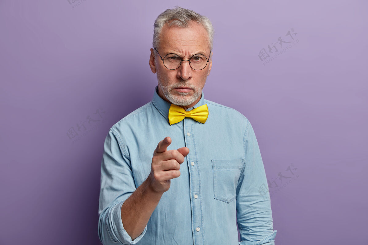 祖父严肃的老人穿着优雅的衬衫 打着黄色领结 对同事的低效工作感到不满皱纹领结人