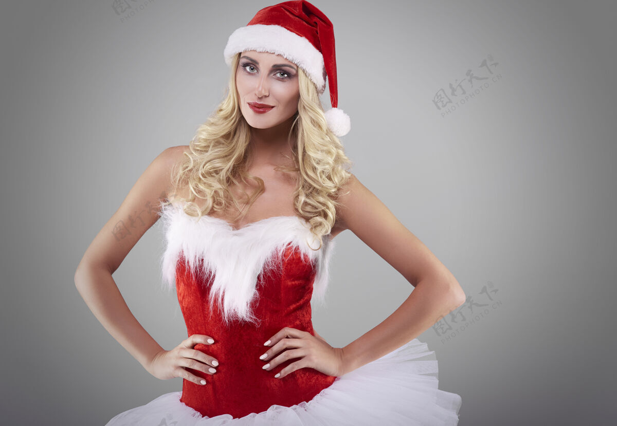 站着灰墙上穿圣诞老人服装的性感女人严肃女人微笑