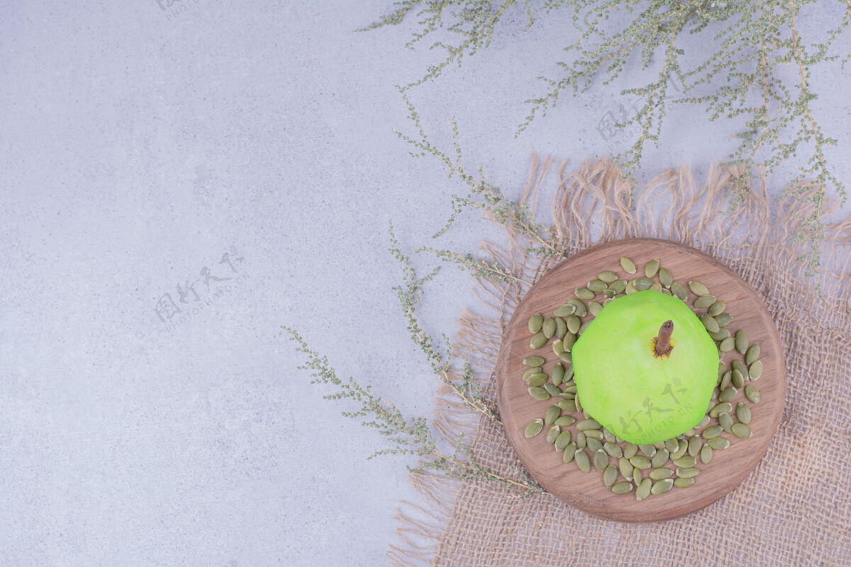 季节一个绿色的梨放在木板上 周围有南瓜子美味水果生物
