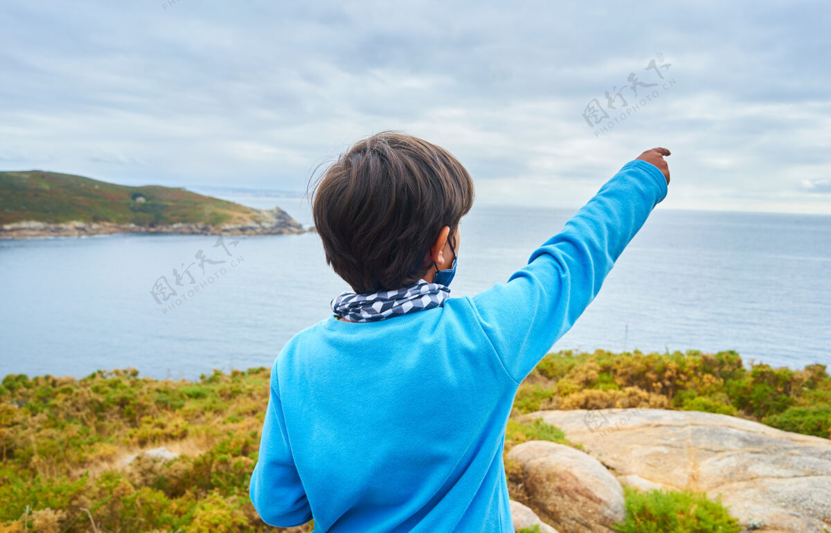 户外一个小男孩站在海景背景上的浅焦镜头年轻人度假