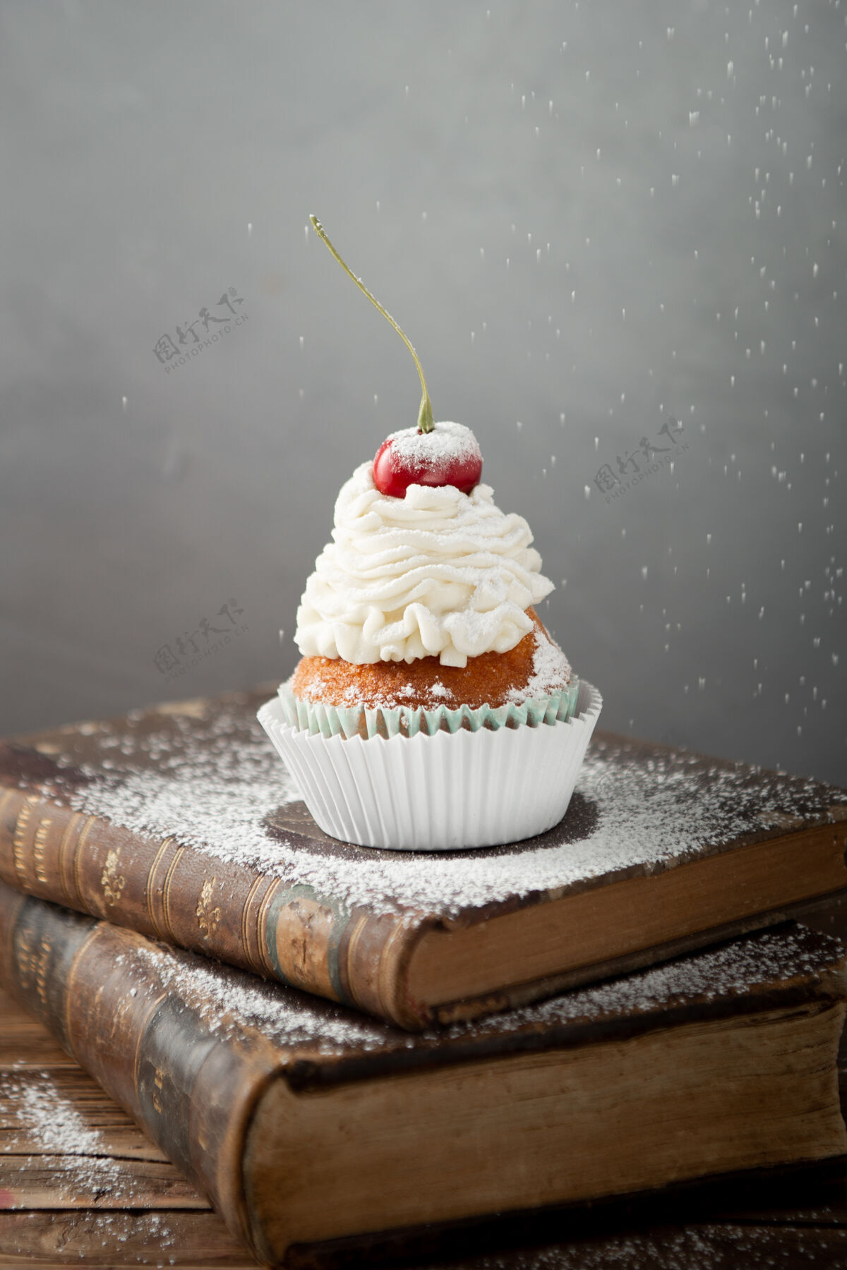 小吃一个美味的纸杯蛋糕与奶油和樱桃上的书垂直拍摄樱桃新鲜糖