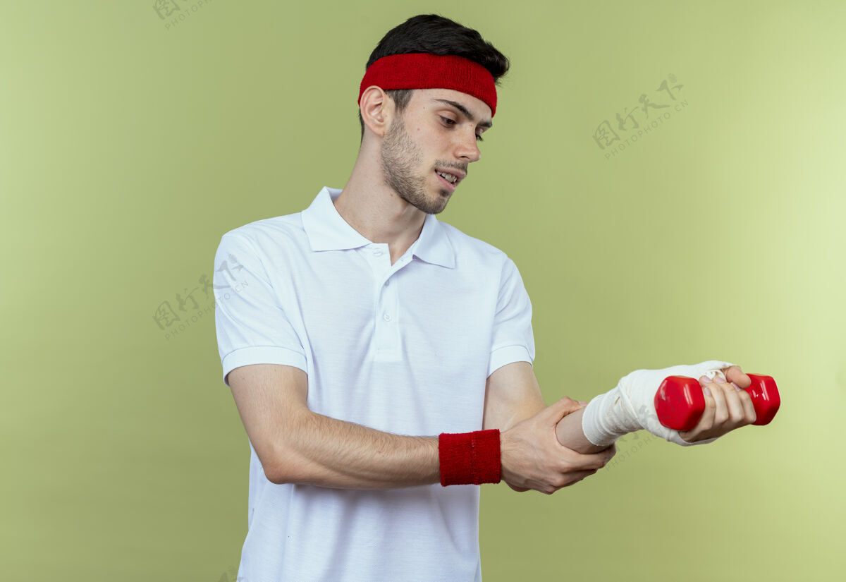 触摸戴着头巾的年轻运动型男子抚摸着缠着绷带的手腕 感到绿色的疼痛感觉站立绿色