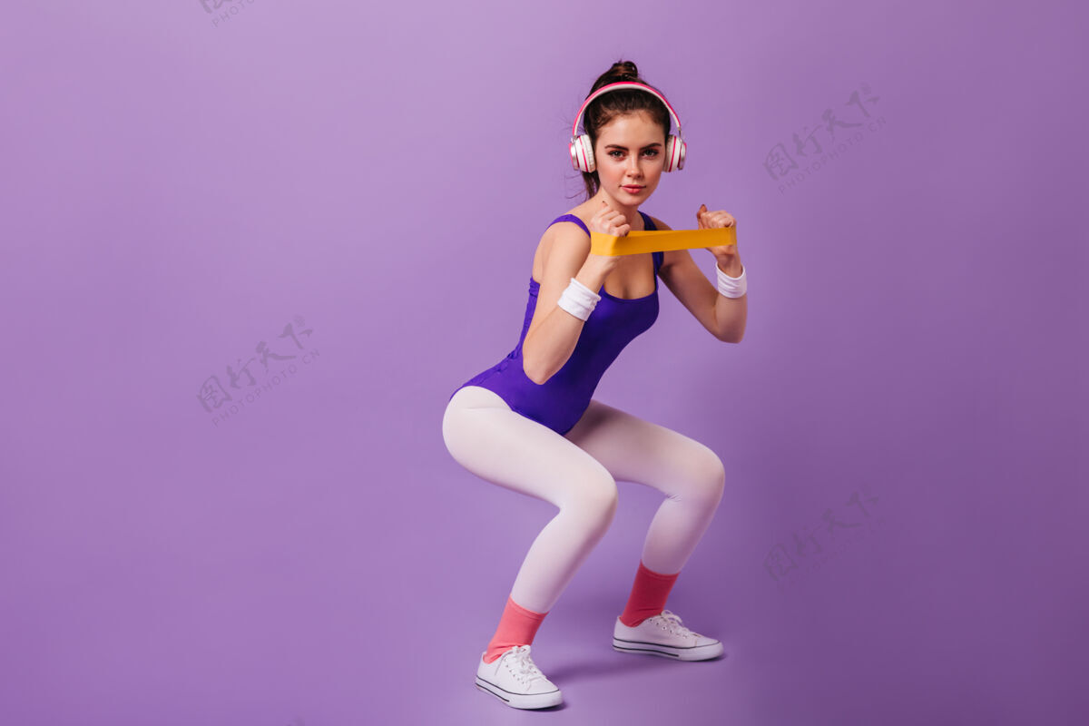 模特在紫色墙上从事体育运动的苗条女人健身球漂亮女性