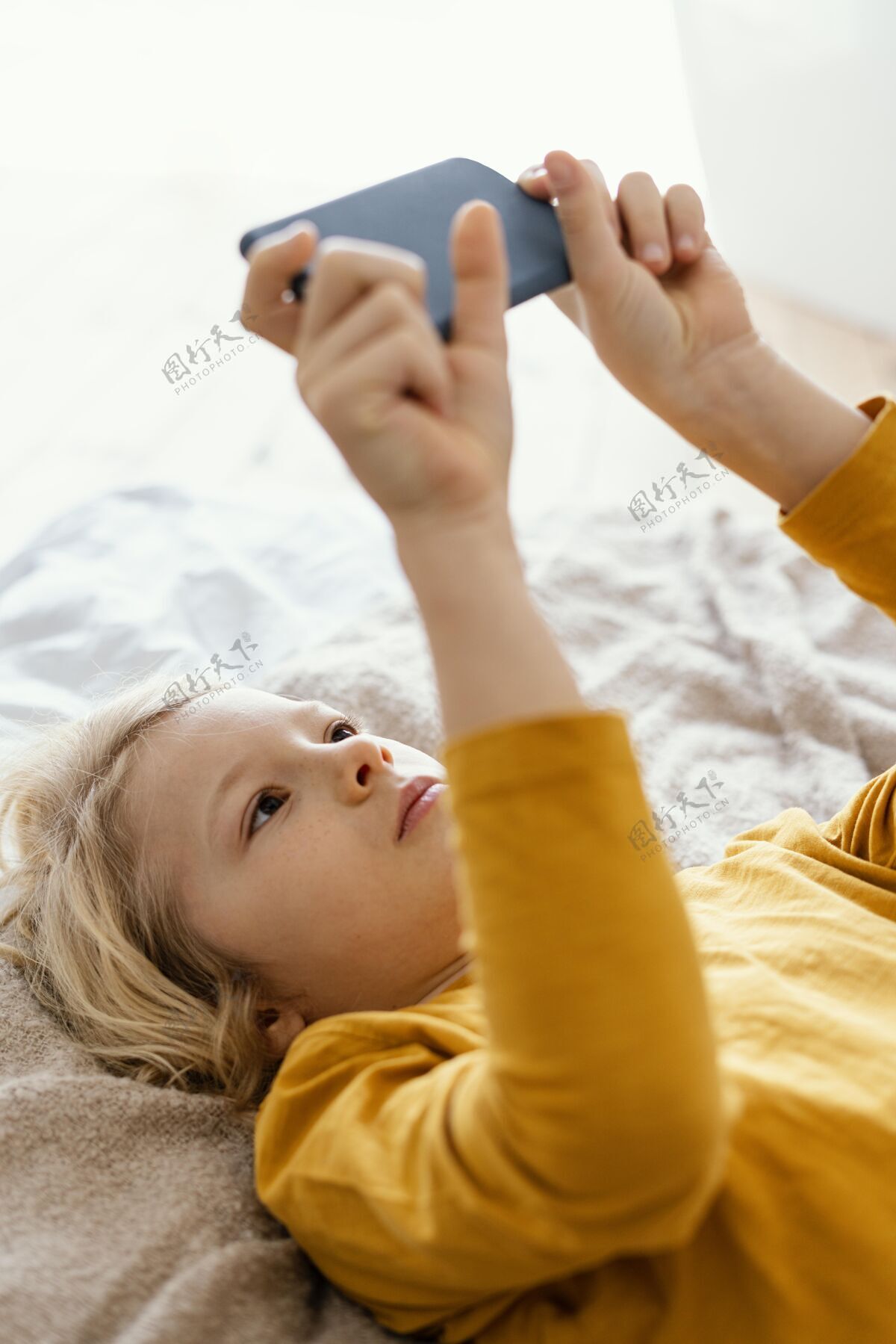 孩子孩子在床上玩手机设备科技房子