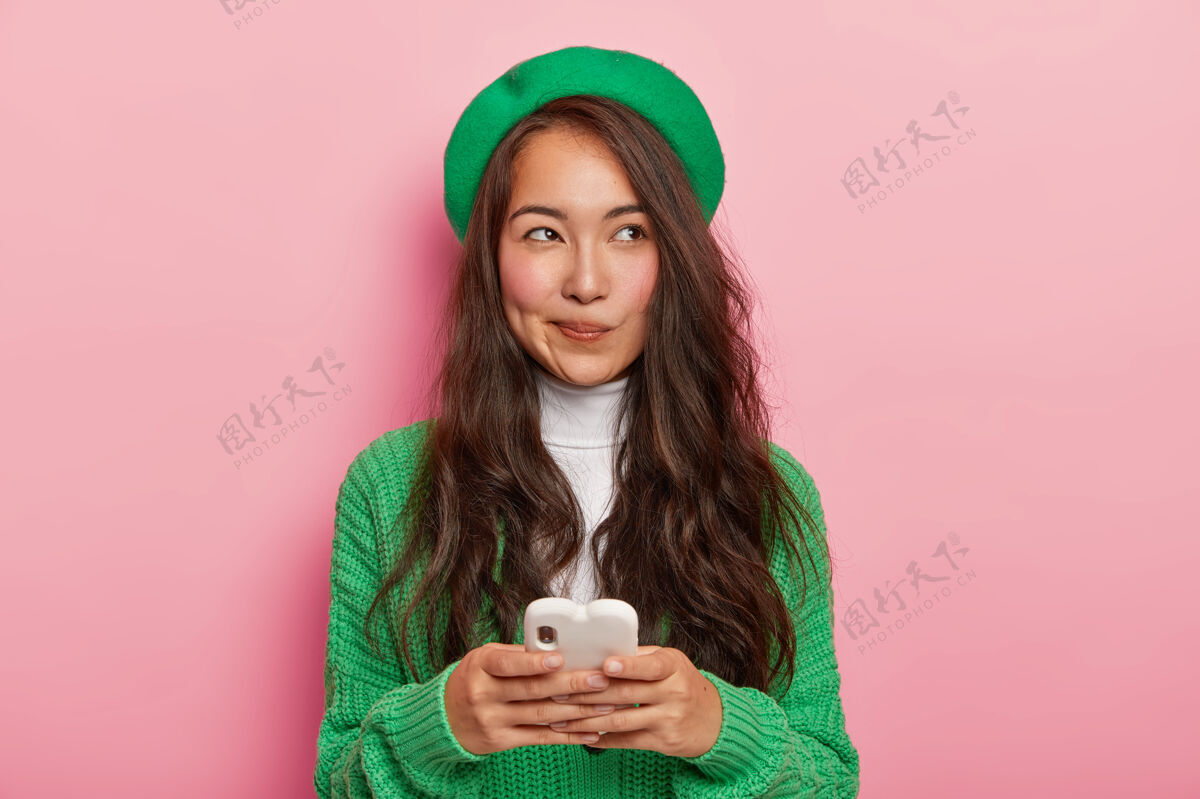 肖像漂亮的黑发日本女人用现代手机发短信 上网 有体贴的表情个人旁白女性