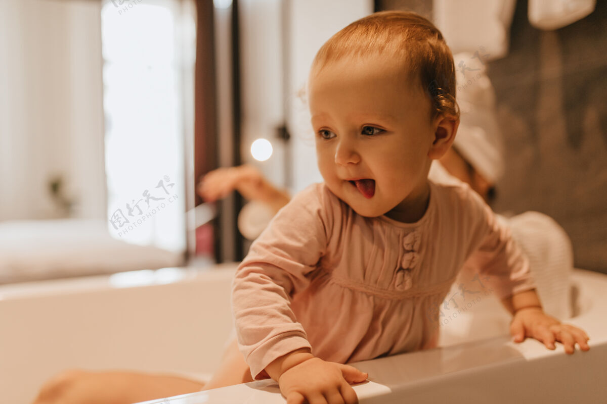 长袍穿着粉色上衣的好奇金发孩子在浴室里饶有兴致地学习物品的快照浴室肖像年轻人