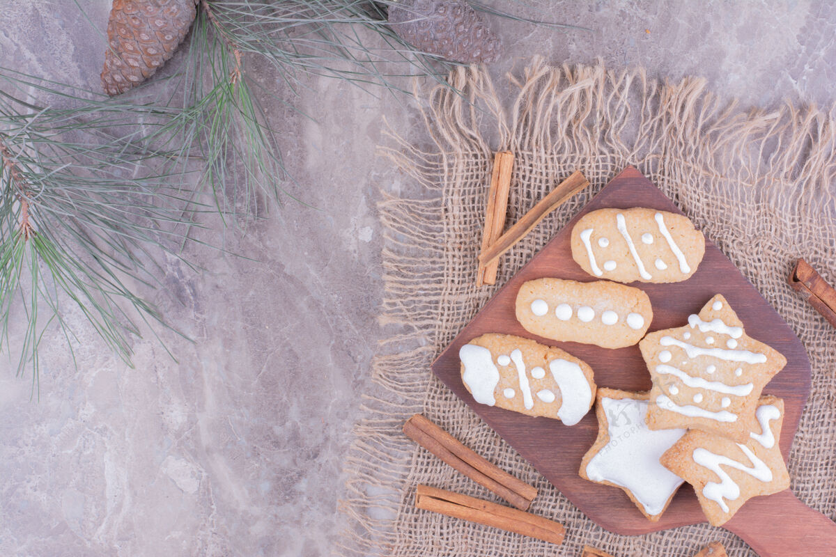 圣诞节圣诞姜饼呈椭圆形和星形 放在木板上 周围放着肉桂棒喜悦饼干烹饪
