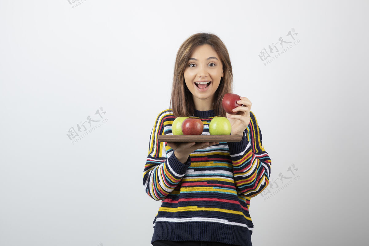 看一个穿着便服 手里拿着一堆苹果的可爱的年轻女人抱水果模特