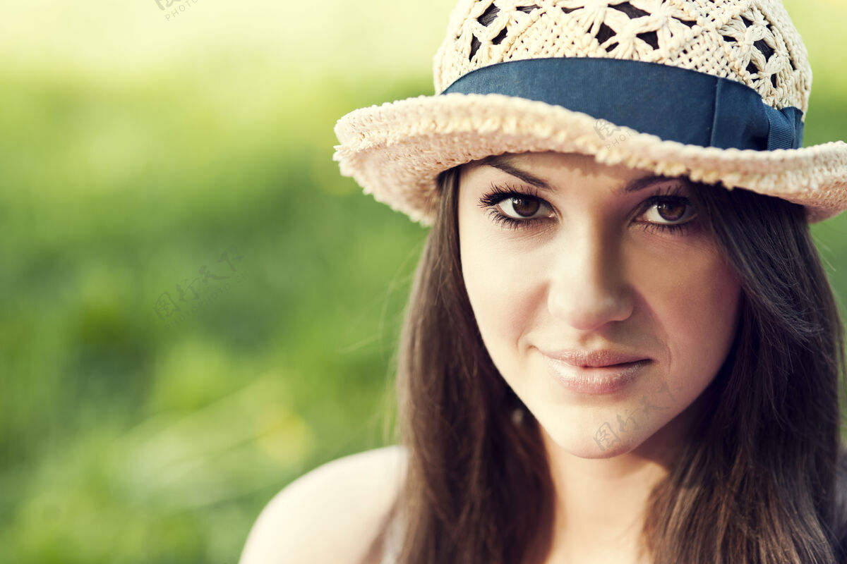 软呢帽在公园里享受夏天的年轻女子触摸帽子躺着