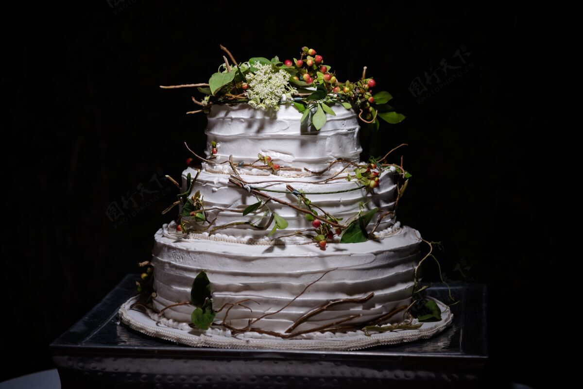 分支特写一个乡村婚礼蛋糕与绿叶 树枝和小圆形浆果花活动奶油