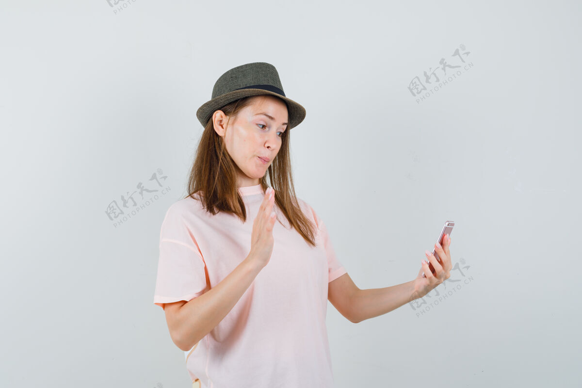 小穿着粉色t恤 戴着帽子的年轻女孩在视频聊天中挥舞着手 看上去很快乐 正面视图可爱漂亮女人