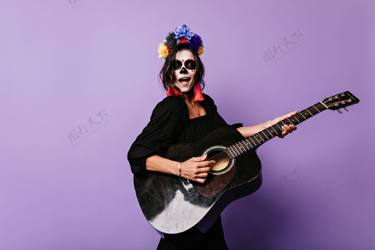 人物脸上带着艺术气息的女孩唱着小夜曲 弹着吉他万圣节头骨庆典