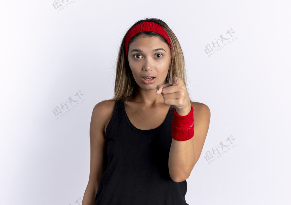 头带穿着黑色运动服 头戴红色头巾 食指指着的年轻健身女孩站在白色的墙壁上惊讶不已手指目录运动装