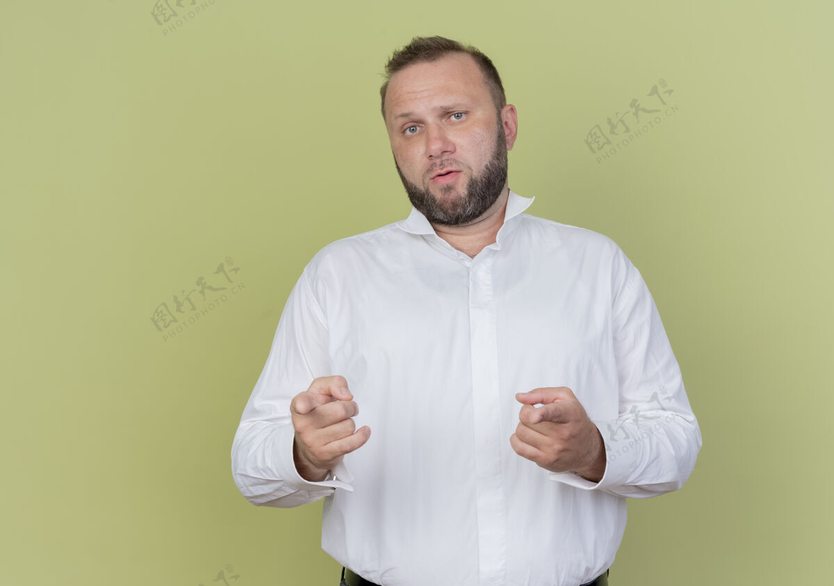 光一个留着胡子的男人穿着白衬衫 用食指指着 站在光墙上 看起来很困惑手指指点站