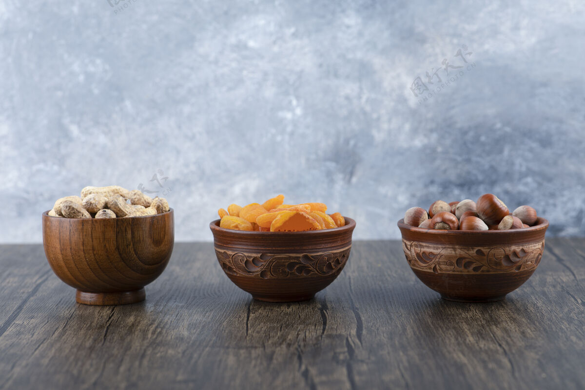 盐木桌上摆满了健康坚果和杏干的木碗果皮食物无皮