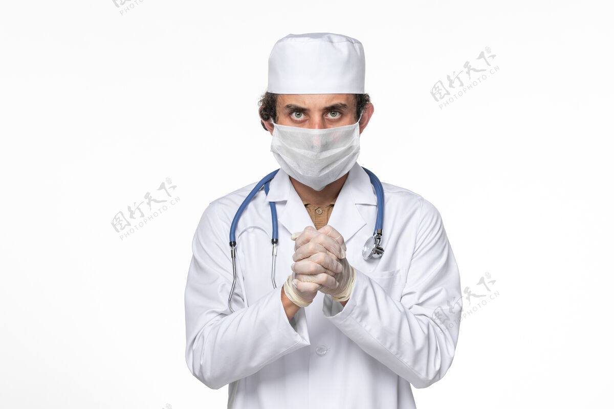 大流行正面图：男医生穿着医疗服 戴着口罩 以防白墙病毒溅起大流行男性听诊器冠状病毒