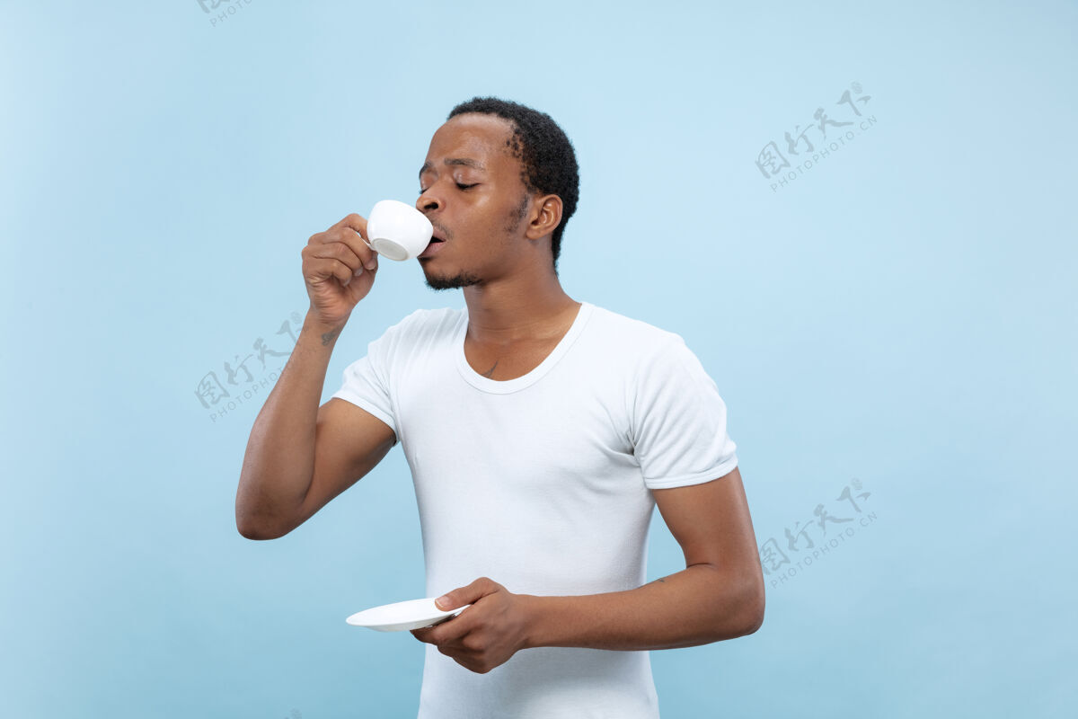 企业家半身特写肖像的年轻非洲裔美国人在白衬衫上的蓝色空间饮酒人类职业