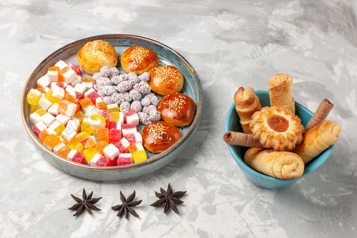 生的正面图：糖糖果 浅白色表面上有小甜面包和百吉饼甜点饼干甜点饼干早餐水果浅白色