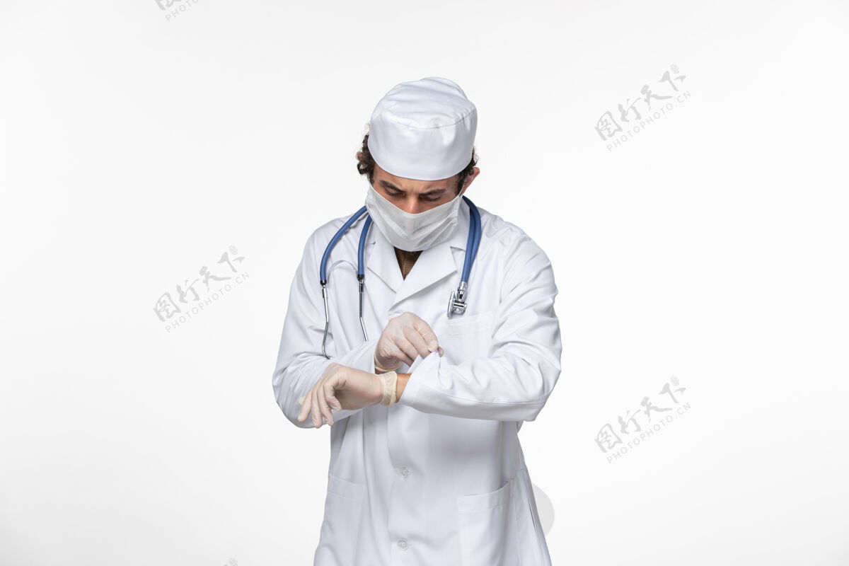 消毒正面图男医生穿着医用西服 戴着无菌口罩作为防护罩 看着自己手腕上的白壁病毒冠状病毒大流行疾病青年工人专家
