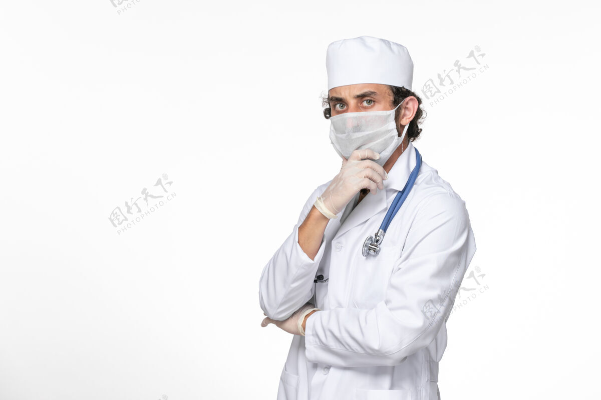 防护正面图：男医生穿着医疗服 戴着无菌口罩 以防被冠状病毒感染摆姿势思考白墙飞溅病毒冠状病毒大流行的健康问题病毒冠状病毒思考