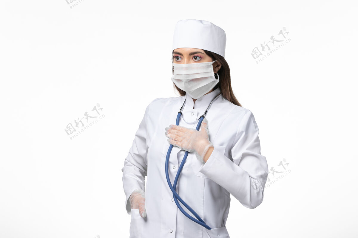 视图正面图女医生身穿白色无菌医疗服 带口罩 因白墙上冠状病毒病冠状病毒-大流行病毒病套装冠状病毒专业