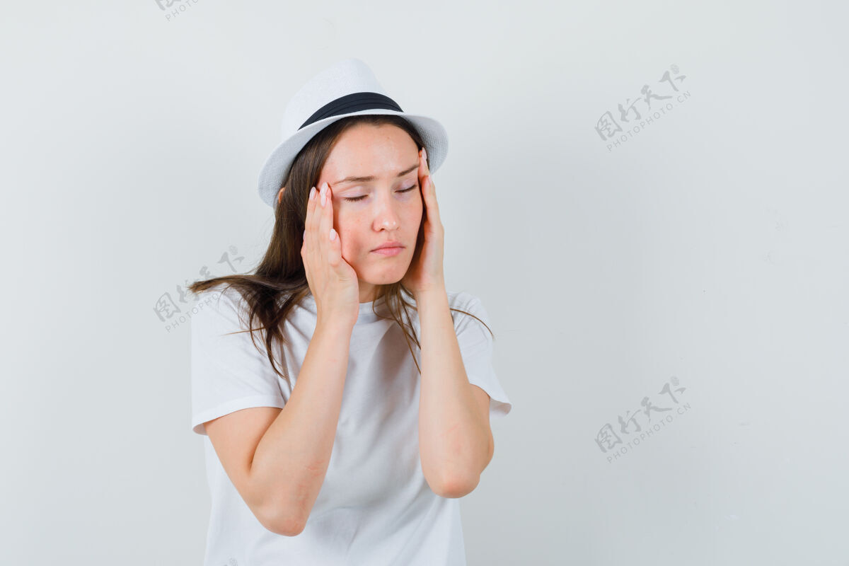 随意年轻女孩穿着白色t恤 戴着帽子揉着太阳穴 看上去很疲惫 前视图寺庙童年积极