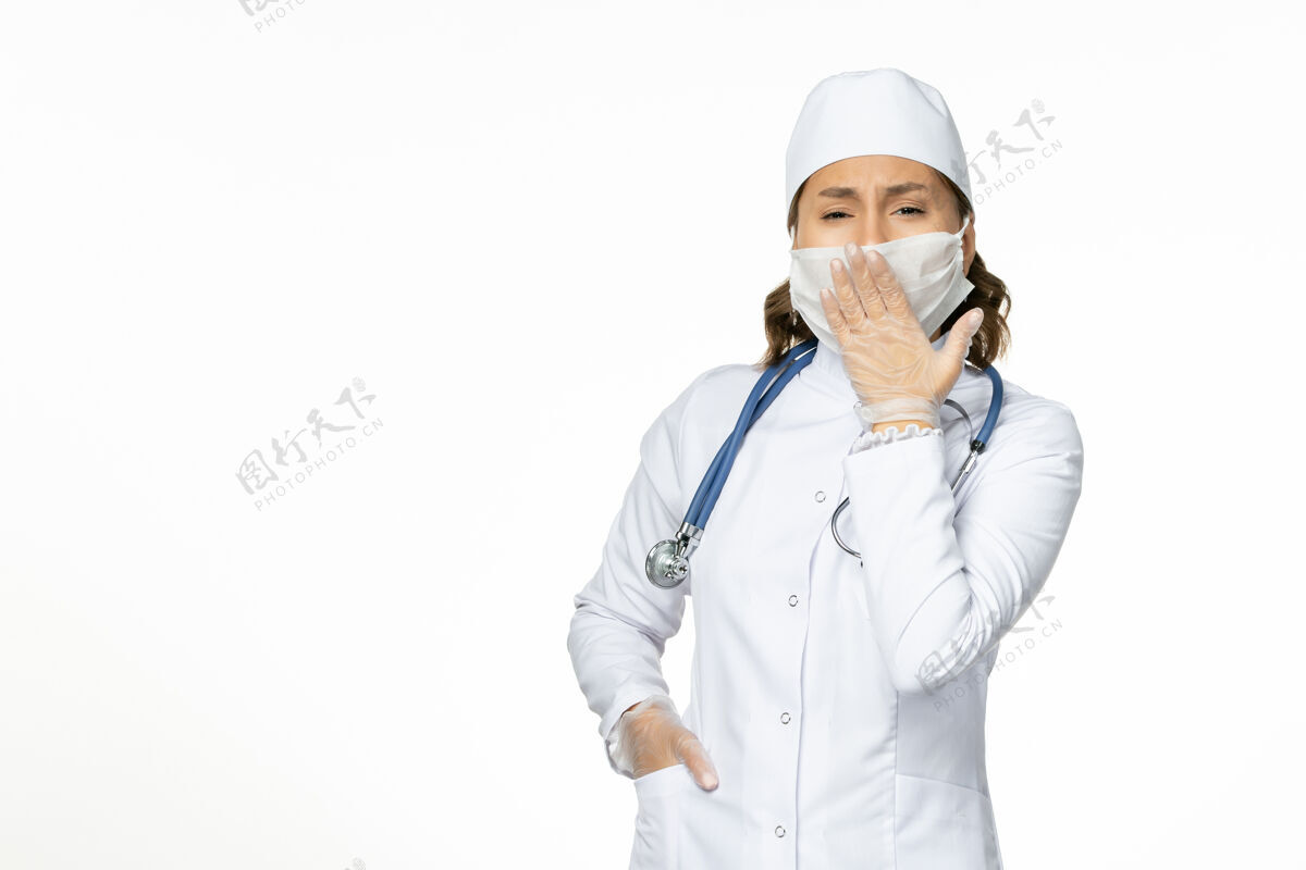 冠状病毒正面图女医生身穿白色医疗服 戴口罩因冠状病毒打呵欠白墙大流行疾病隔离冠状病毒大流行西装药品