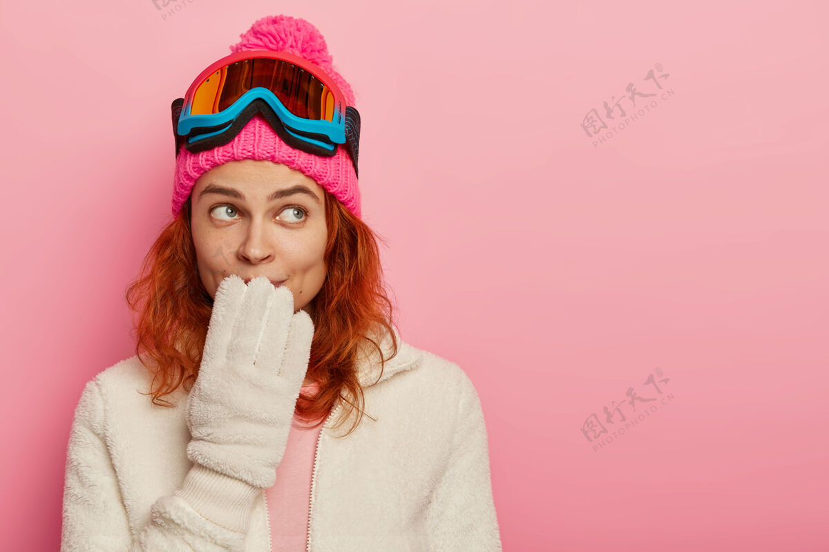 室内滑雪板女子的肖像有体贴的表情 手放在嘴上 戴着冬天的帽子 白手套冬天客场站