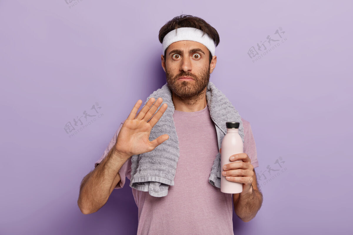 休闲年轻的运动员做出拒绝的手势 要求不要打扰他 穿着运动服 戴着白色的头巾 围着脖子 拿着一瓶淡水汗水手掌运动