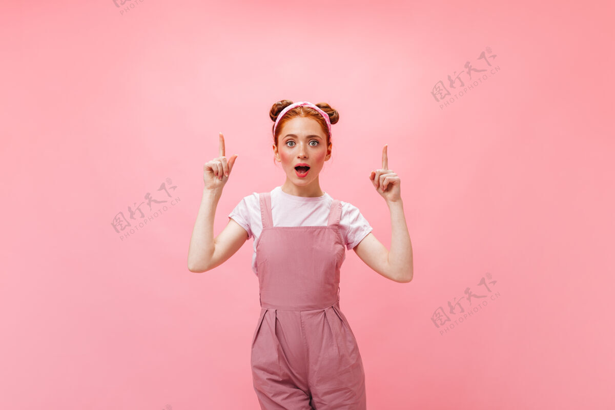 女性穿粉红色连身衣的女人想到了粉红色背景上的年轻红发女人的肖像粉色背景白色t恤工装