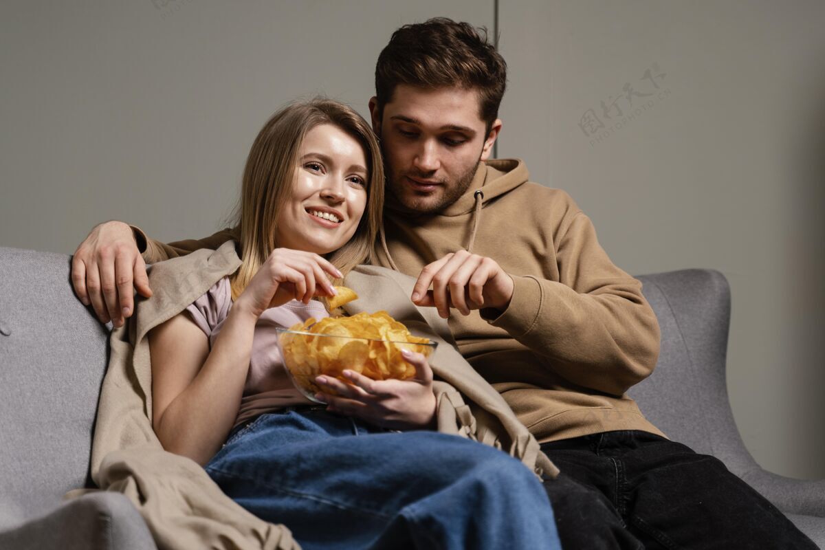 薯片夫妻俩在沙发上看电视吃薯片女人毯子室内