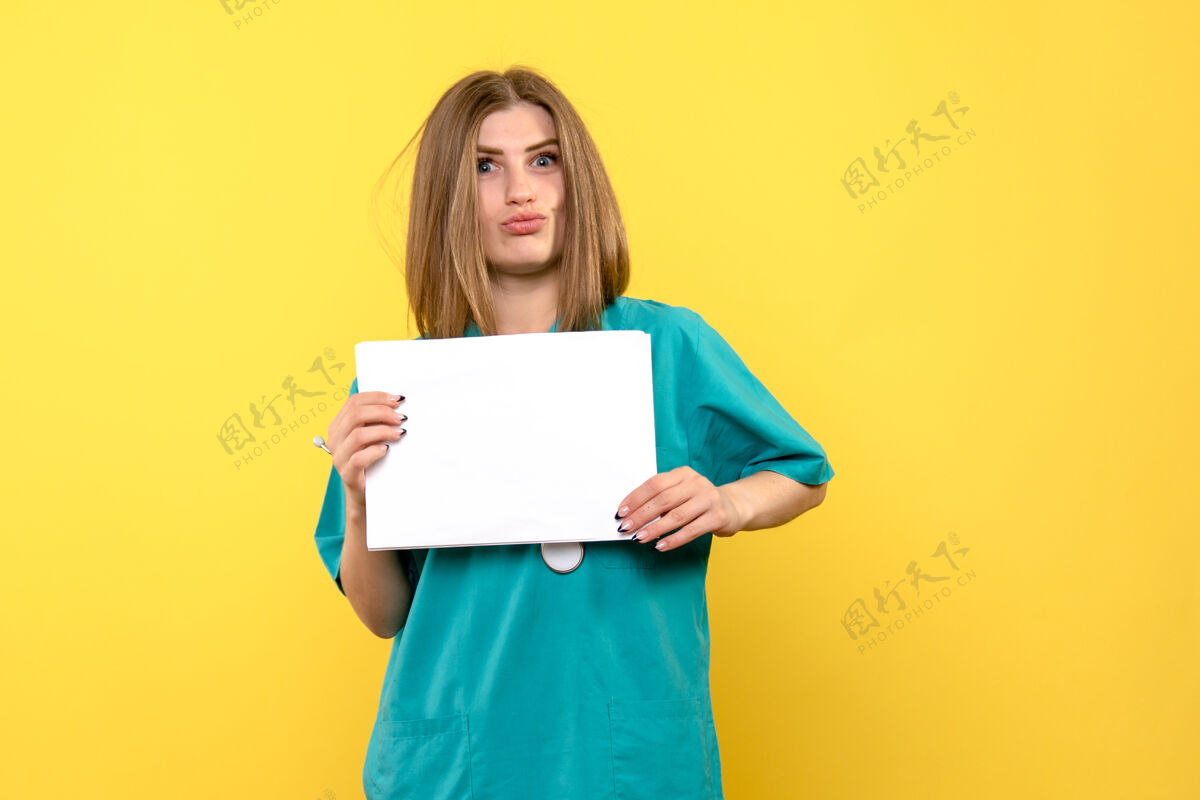微笑黄色墙上拿着文件的年轻女医生的正视图成人持有学生