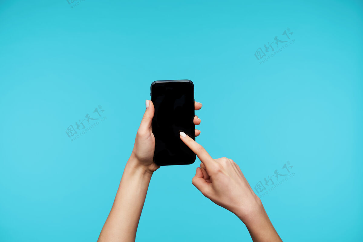 手机用白色美甲在手上特写 保持智能手机并在屏幕上滑动指示器食指电话