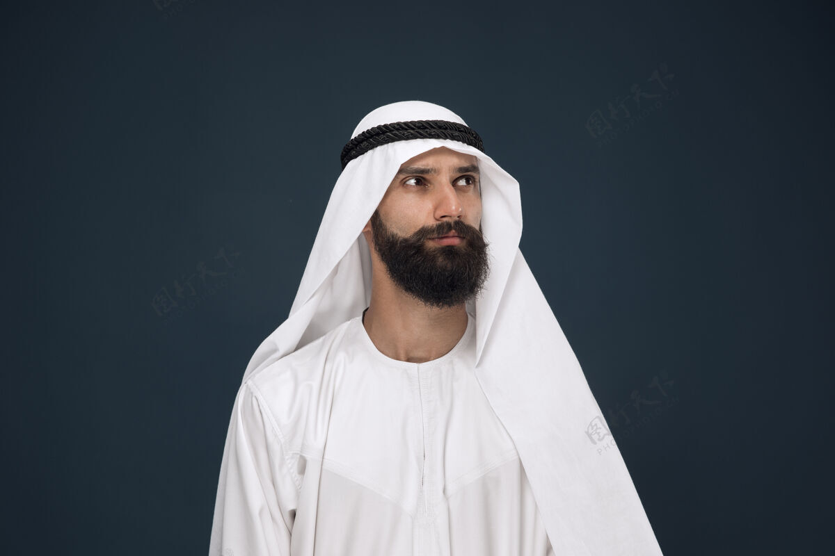 惊奇深蓝色空间上的阿拉伯沙特商人半身像年轻男模站着 看起来很体贴情绪衣服沙特