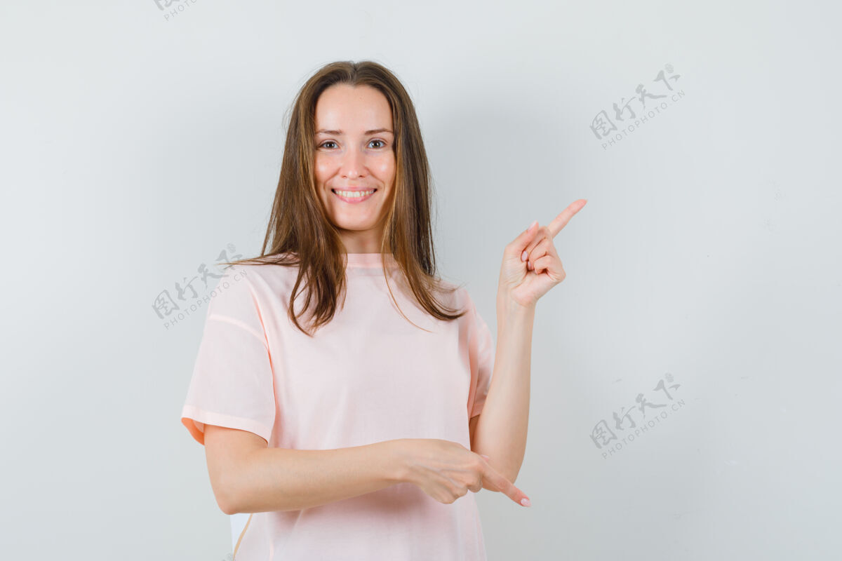 正面穿着粉色t恤的年轻女士上下指指点点 看上去很高兴 正前方的景色时尚优雅手指