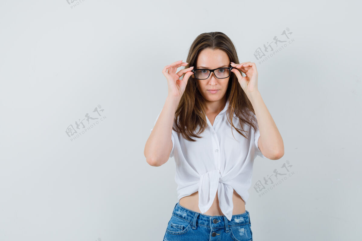 积极年轻女士调整她的眼镜在白色上衣 眼镜 前视图友谊室内肖像