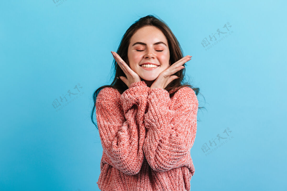 女性可爱的黑发女孩闭着眼睛微笑的特写照片穿着粉色毛衣的女孩轻轻地抚摸她的脸颊可爱脸完美