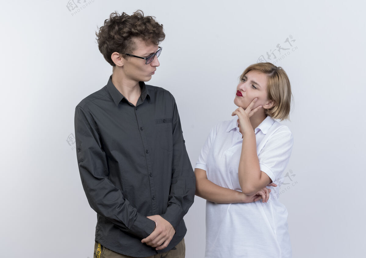 夫妻一对年轻夫妇站在白墙上 带着怀疑的表情看着对方站着表情女人