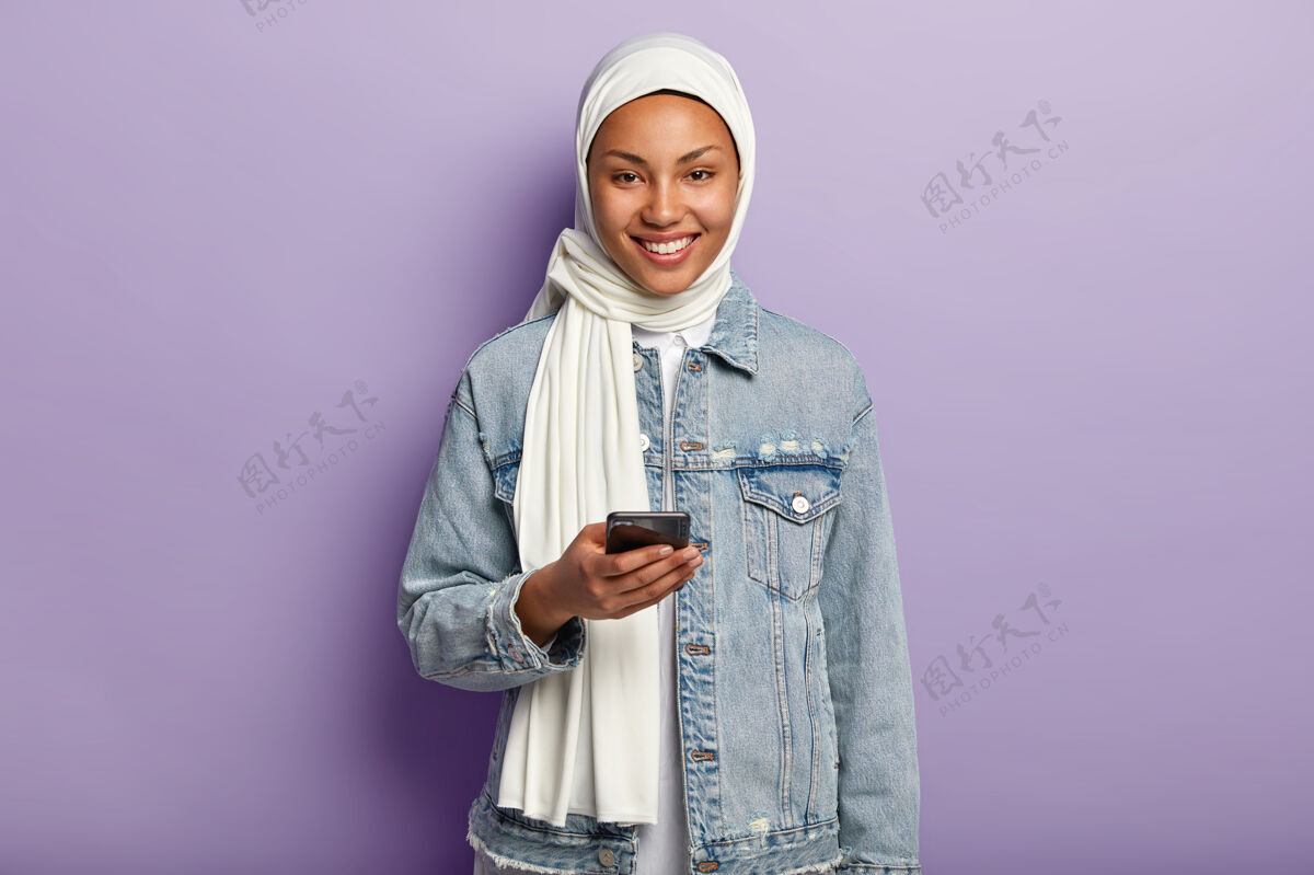 休闲快乐的年轻穆斯林妇女与她的手机合影的肖像肖像年轻人牛仔