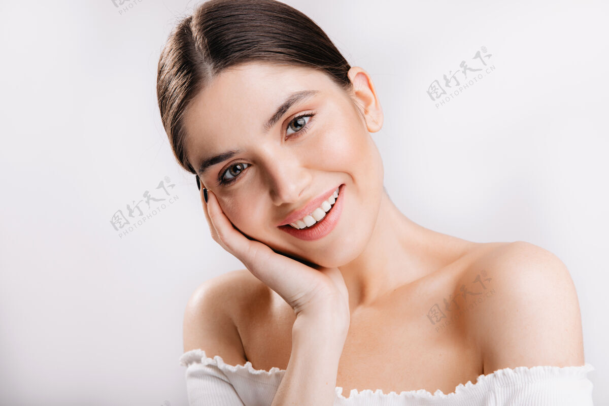 年轻健康皮肤的微笑女孩的肖像白墙上可爱的黑发女人平静眉毛光滑